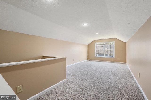 bonus room with a textured ceiling, lofted ceiling, and carpet