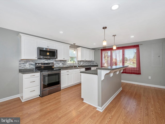 kitchen featuring sink, decorative light fixtures, appliances with stainless steel finishes, white cabinets, and backsplash