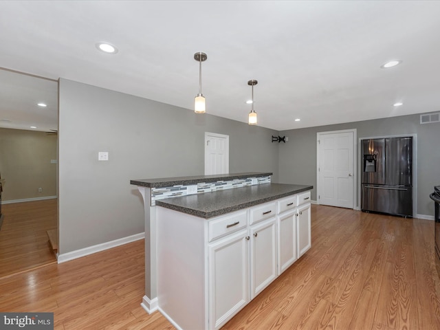 kitchen featuring stainless steel refrigerator with ice dispenser, white cabinetry, a center island, light hardwood / wood-style flooring, and pendant lighting