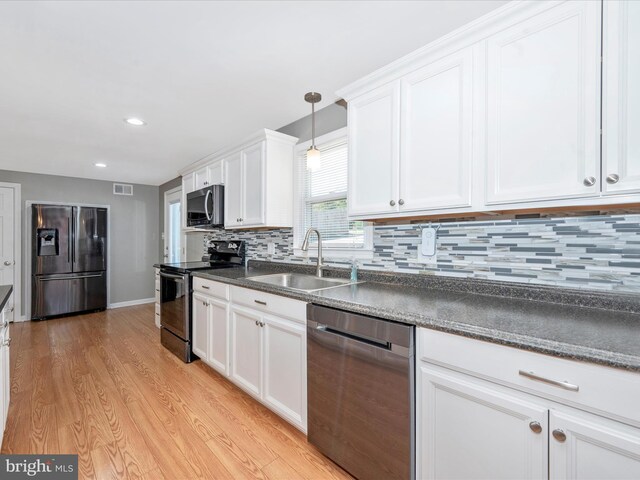 kitchen with sink, white cabinetry, light hardwood / wood-style flooring, appliances with stainless steel finishes, and pendant lighting