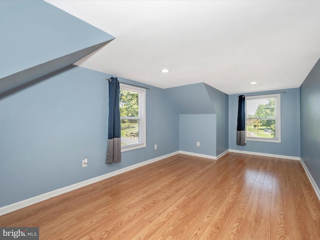 bonus room with vaulted ceiling, a wealth of natural light, and light hardwood / wood-style floors