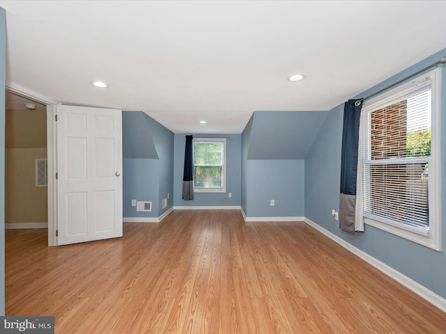 additional living space with vaulted ceiling and light hardwood / wood-style floors