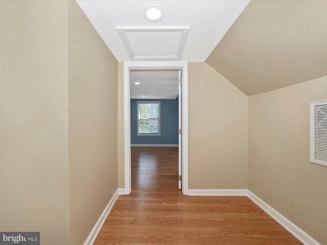 corridor with light hardwood / wood-style flooring and vaulted ceiling