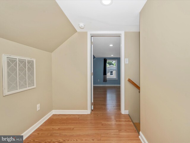 corridor with vaulted ceiling and light wood-type flooring