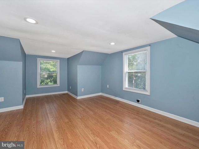 bonus room with vaulted ceiling and light wood-type flooring