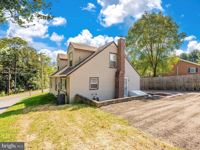 view of side of home with cooling unit and a lawn