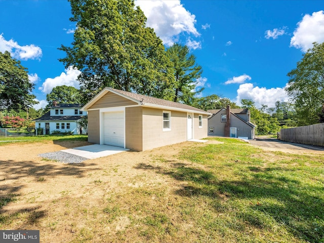 back of property with a garage, an outbuilding, and a lawn