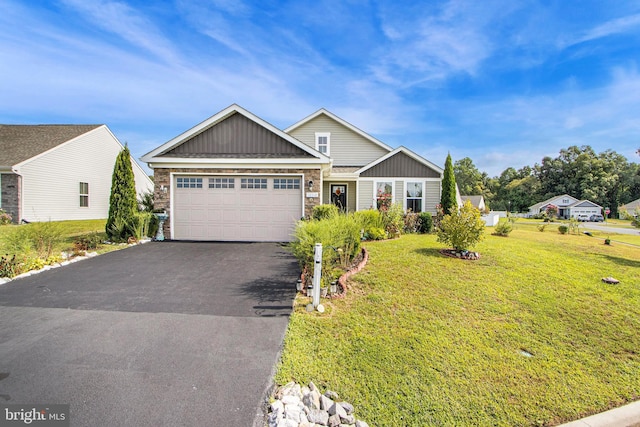 view of front facade with driveway, a front lawn, an attached garage, and stone siding