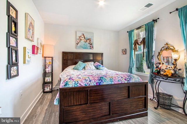 bedroom featuring visible vents, baseboards, and wood finished floors