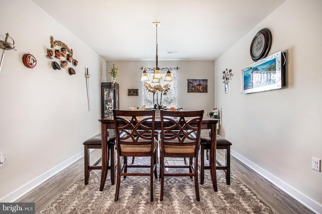 dining space with dark wood-style floors, a chandelier, visible vents, and baseboards