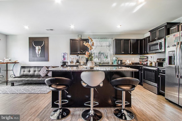 kitchen featuring appliances with stainless steel finishes, a center island, visible vents, and a kitchen breakfast bar