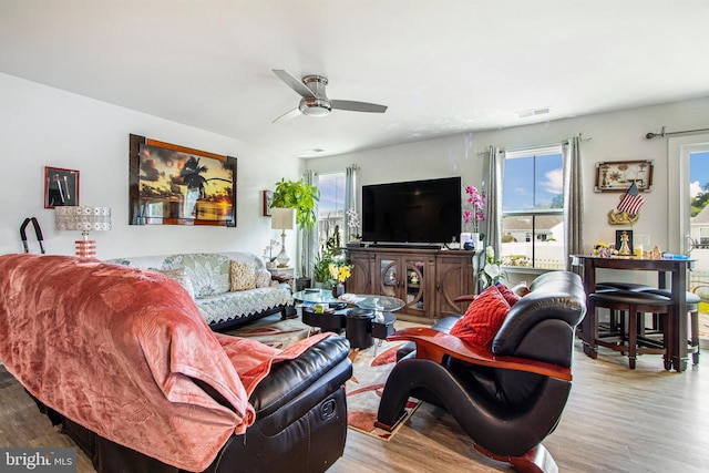 living area with ceiling fan, visible vents, and wood finished floors