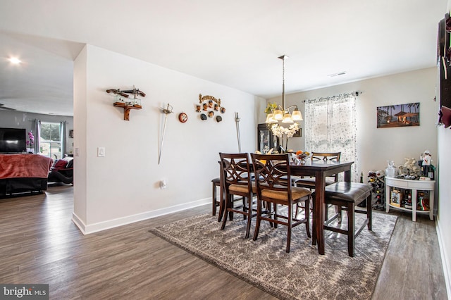 dining space featuring dark wood-type flooring and a chandelier