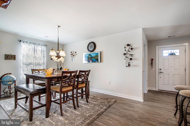 dining area with dark hardwood / wood-style flooring, a notable chandelier, and a healthy amount of sunlight