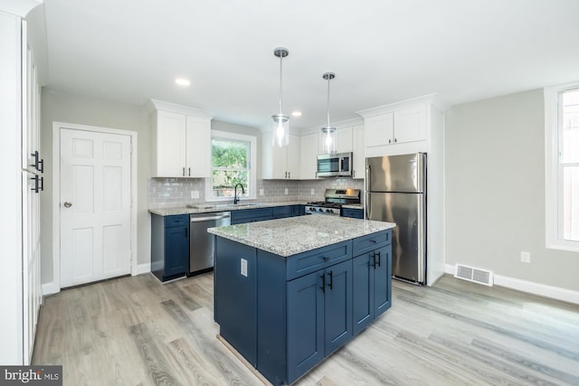 kitchen featuring blue cabinetry, appliances with stainless steel finishes, white cabinets, and a center island