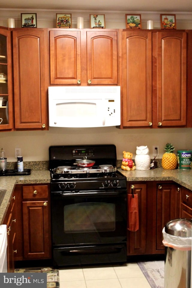 kitchen featuring light tile patterned flooring, light stone countertops, and black gas stove