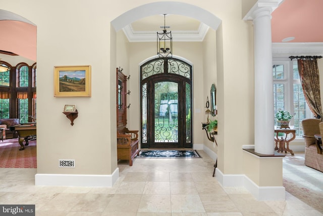 foyer featuring a towering ceiling, a wealth of natural light, baseboards, and crown molding