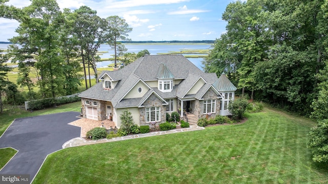 view of front of house with stone siding, aphalt driveway, a water view, and a front yard