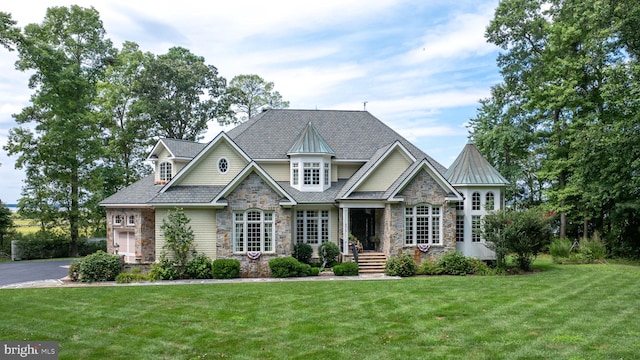 craftsman house with stone siding, a front lawn, and a standing seam roof