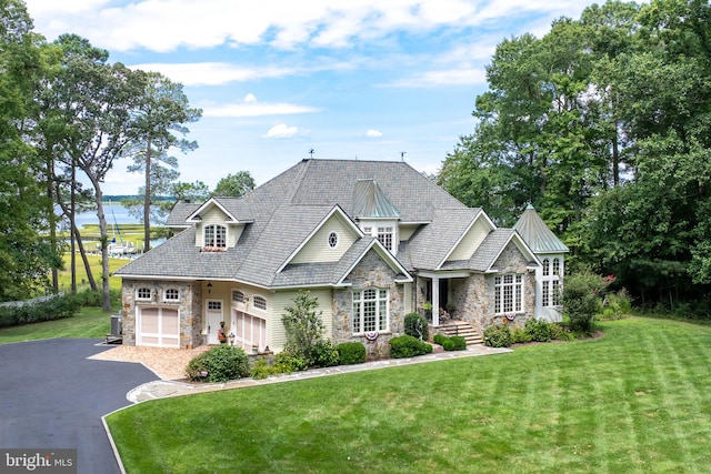 view of front facade with a garage, stone siding, aphalt driveway, and a front yard