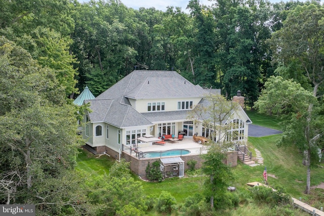 back of property with stairs, an outdoor hangout area, a lawn, and a patio