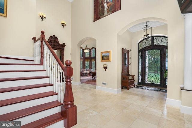 entryway with baseboards, a high ceiling, arched walkways, and ornamental molding