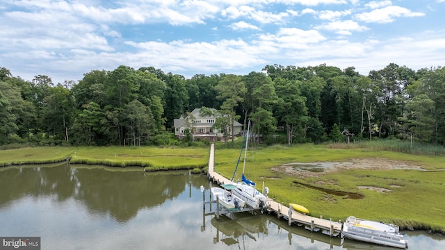 dock area featuring a lawn, a water view, boat lift, and a view of trees