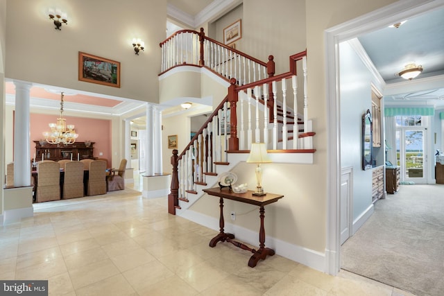 foyer entrance with ornate columns, a notable chandelier, and crown molding