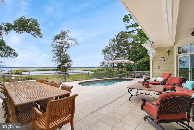 view of pool featuring a fenced in pool, outdoor dining space, a patio area, and a water view