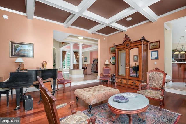 living area with coffered ceiling, wood finished floors, beam ceiling, and ornate columns