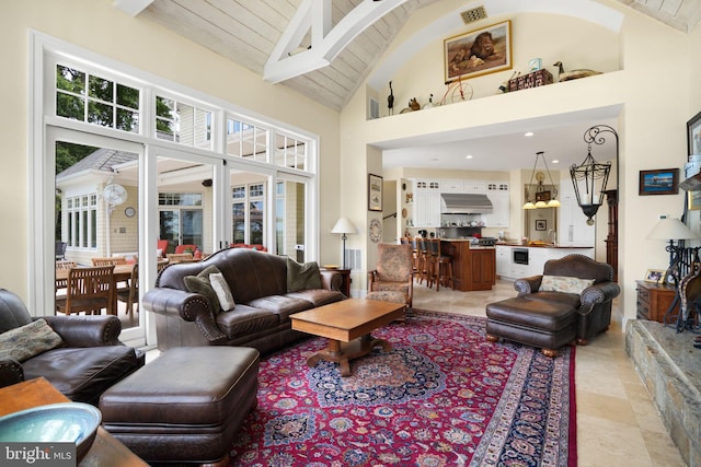 living area with beamed ceiling, wooden ceiling, visible vents, and a healthy amount of sunlight