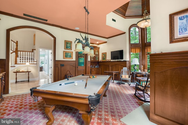 rec room with billiards, arched walkways, wainscoting, a towering ceiling, and ornamental molding