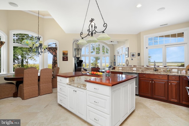 kitchen featuring white cabinets, dishwasher, a center island, hanging light fixtures, and a sink