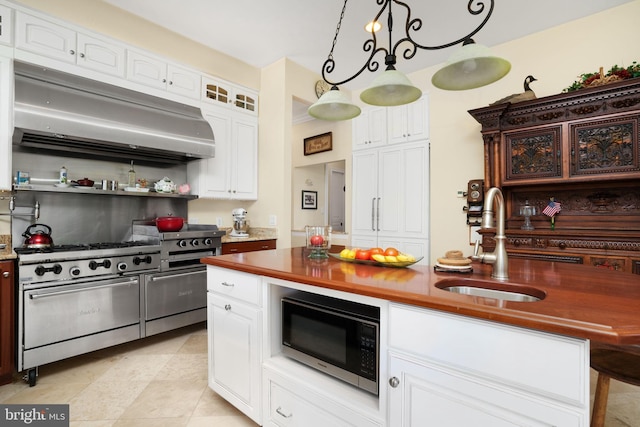 kitchen with under cabinet range hood, a sink, white cabinets, appliances with stainless steel finishes, and pendant lighting