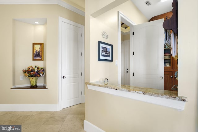 hall featuring ornamental molding, light tile patterned flooring, visible vents, and baseboards