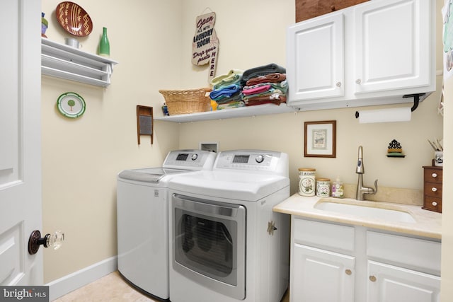 clothes washing area featuring light tile patterned floors, a sink, baseboards, cabinet space, and washer and clothes dryer