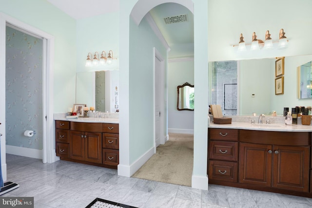 full bath with two vanities, visible vents, a sink, and baseboards