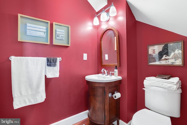 bathroom featuring toilet, vaulted ceiling, and vanity