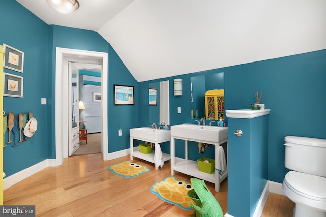 bathroom with lofted ceiling, wood finished floors, toilet, and baseboards