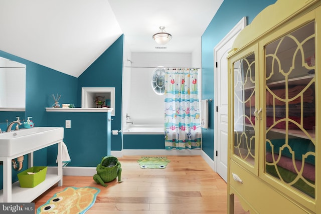 interior space featuring baseboards, vaulted ceiling, and wood finished floors