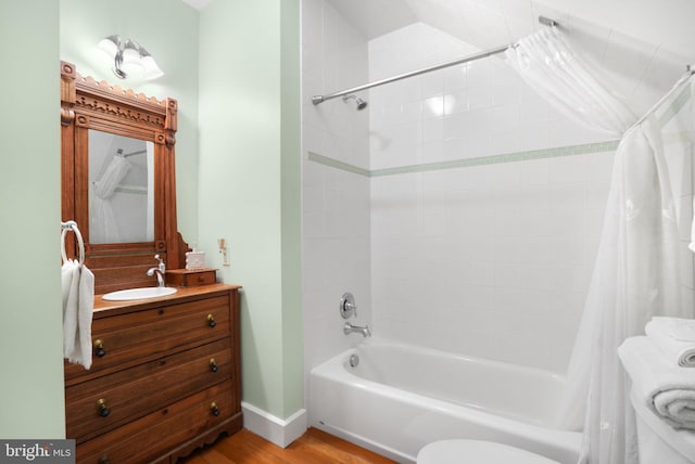 bathroom featuring wood finished floors, shower / tub combo, vanity, and toilet