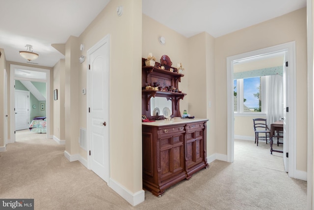 hall featuring light carpet and baseboards