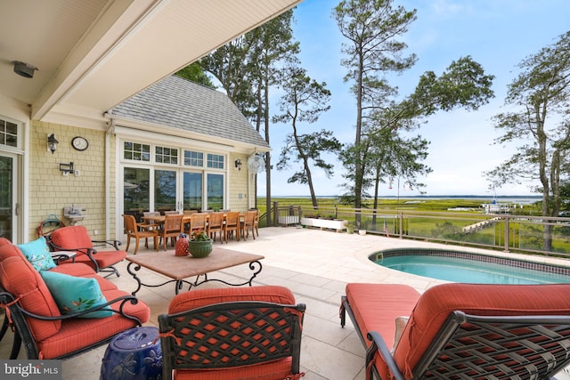 view of pool featuring outdoor dining space, a water view, a patio, and an outdoor living space