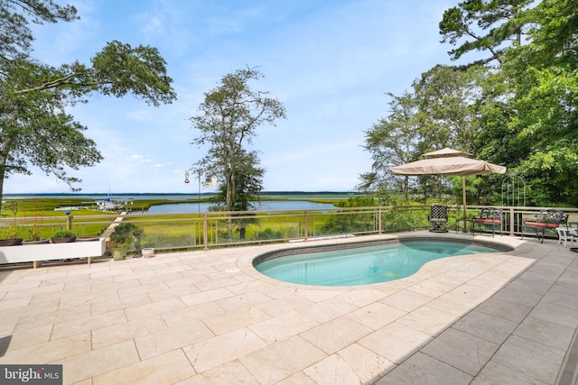 outdoor pool with a patio area and a water view