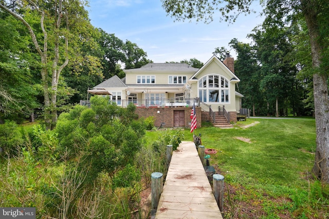 back of property with a chimney and a lawn