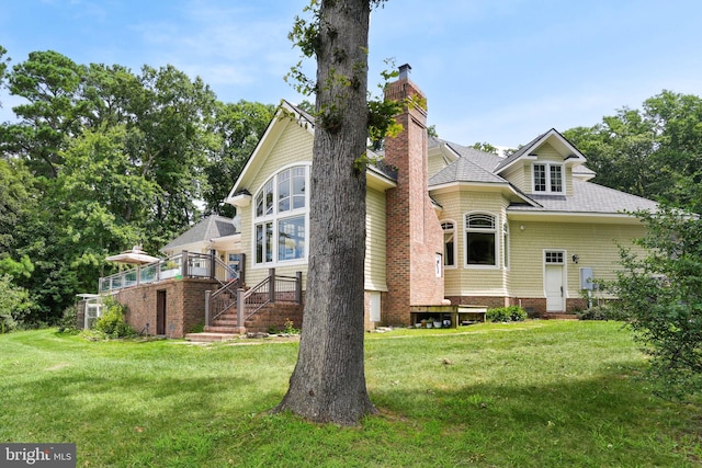 view of front facade featuring a shingled roof, a chimney, and a front lawn