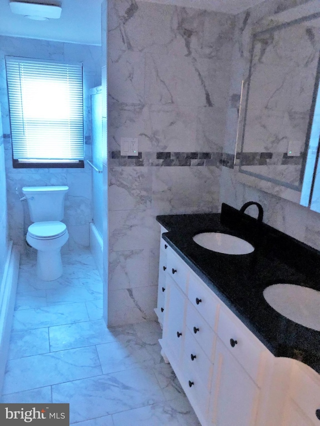 bathroom with vanity, tile walls, and toilet