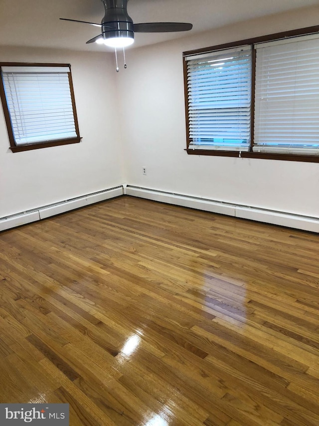 spare room featuring wood-type flooring, a baseboard heating unit, and ceiling fan