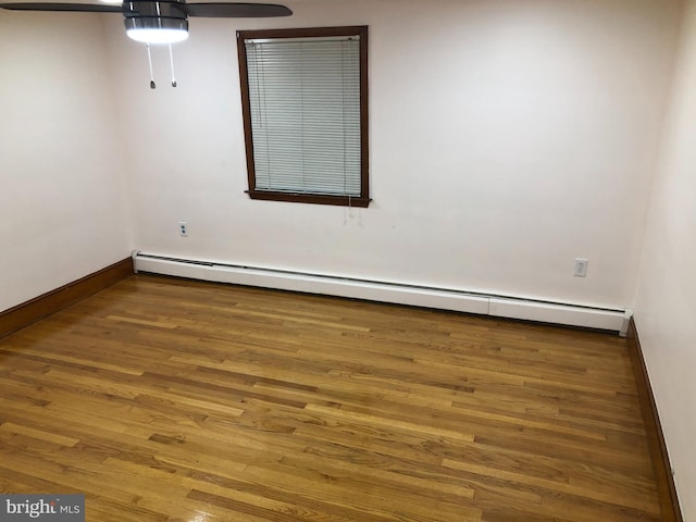 empty room featuring a baseboard heating unit, hardwood / wood-style floors, and ceiling fan