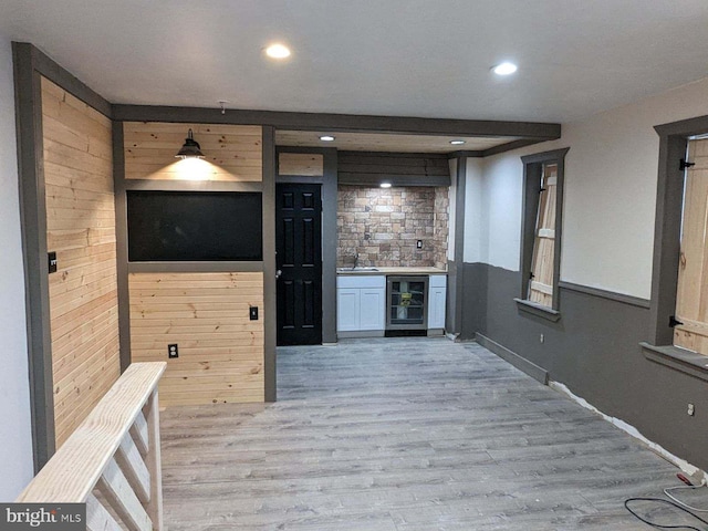 interior space featuring light wood-style flooring, a sink, wood walls, recessed lighting, and wine cooler
